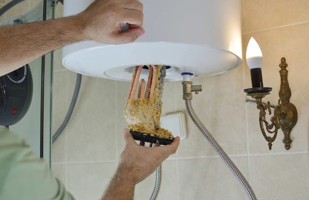 Technician removing mineral buildup from a water heater in York