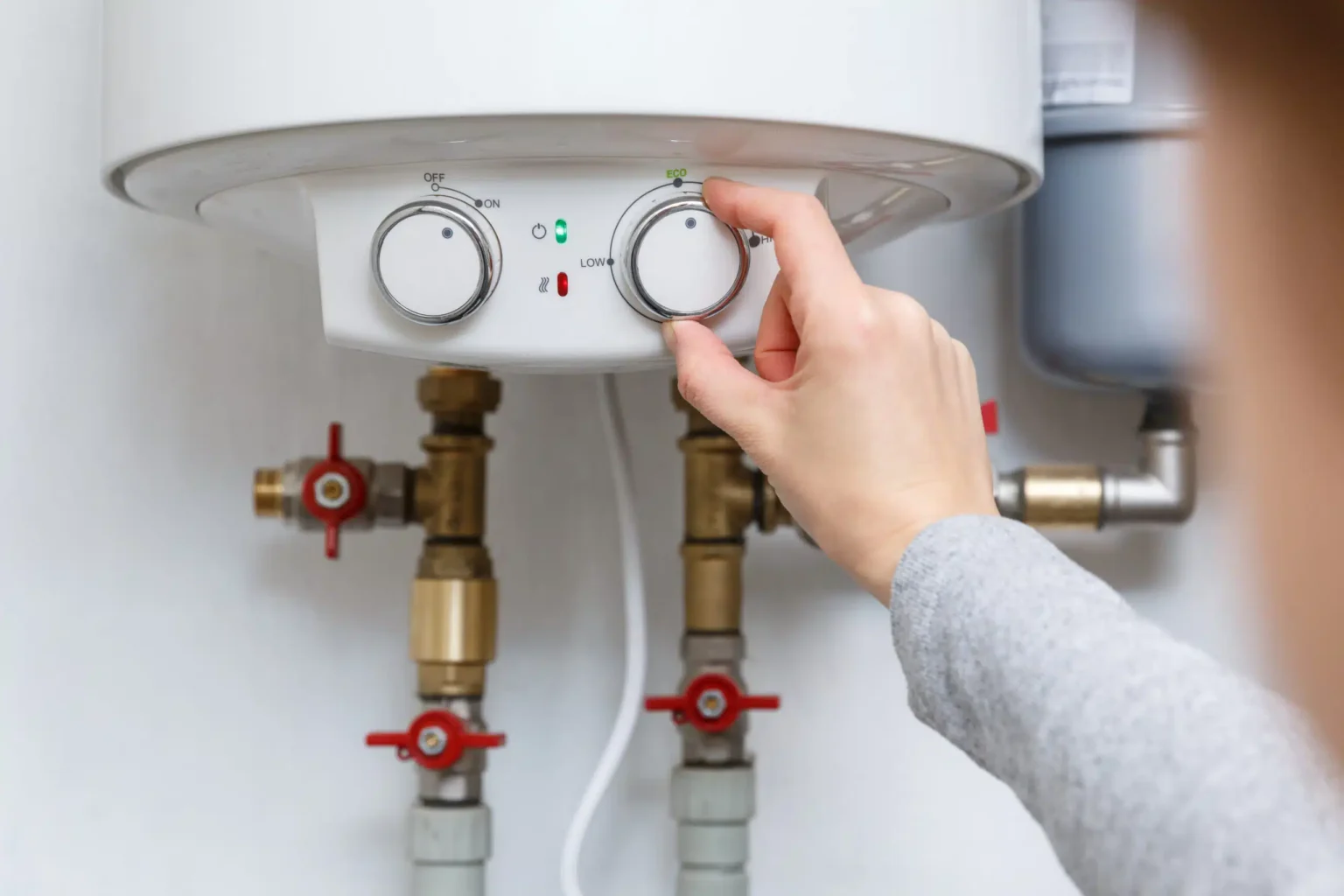 Homeowner adjusting the temperature controls on a water heater in York